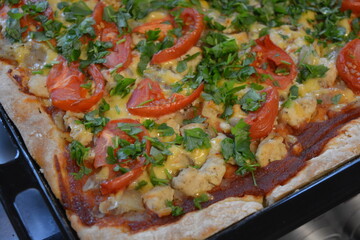 Food, groceries, homemade fresh baked goods. Large pizza with chicken pieces, tomato slices, cheese, and fresh greens.