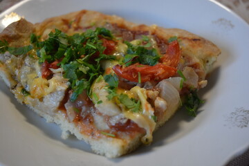 Food, groceries, homemade fresh baked goods. A large slice of pizza with chicken pieces, tomato slices, cheese, and fresh herbs sits on a ceramic plate.
