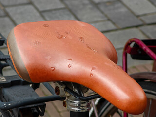 Wet leather bike saddle sitting on a bicycle in a urban area after rain