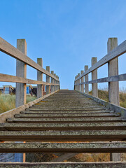Wooden walkway leads to the beach under a clear blue sky during daytime