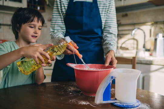 Mother and son cooking pancake dough together in kitchen
