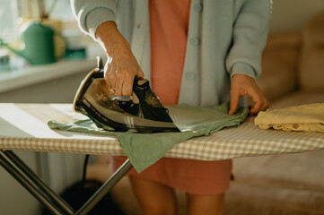 Woman ironing clothes on an ironing board in a comfortable home