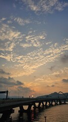 Obraz premium Scenic Bridge at Sunset with Dramatic Clouds Above River