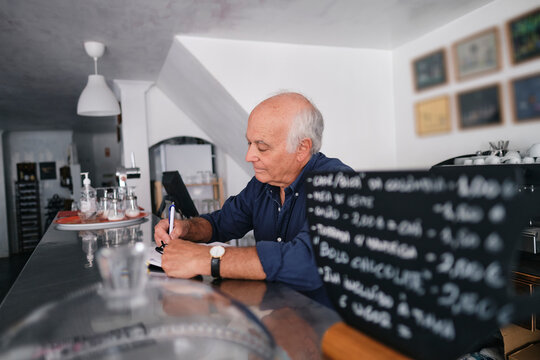 Coffee shop owner writing in diary at cafe