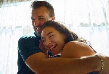 Cheerful couple hugging and laughing together at home