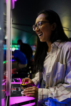 Smiling woman enjoying playing at neon-lit arcade indoors