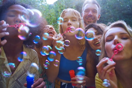Friends enjoying bubbles at a summer outdoor party having fun together