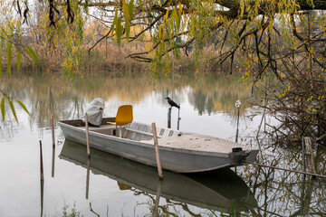 Quiet boat moored at serene lake surrounded by autumn trees in a peaceful setting