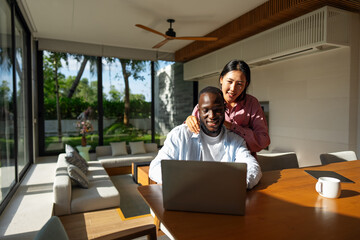Multiethnic freelancer couple enjoy the environment of tropical climate, working on laptop together