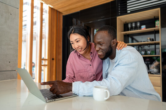 Happy multiethnic couple with laptop making plan for investments, savings and budget for bills - Powered by Adobe