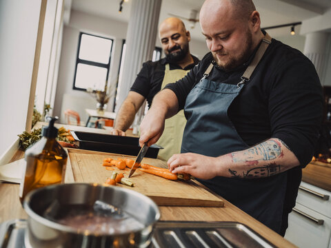 Two people practicing cooking skills in a kitchen cooking class