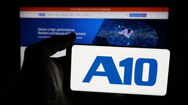 Stuttgart, Germany - 11-12-2025: Person holding mobile phone with logo of US company A10 Networks Inc. on screen in front of web page. Focus on phone display.