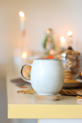 Lit candles, cookies, chocolate, nuts, tea, wine, pumpkins, books, reading glasses and autumn leaves on the table. Autumnal hygge at home. Selective focus.