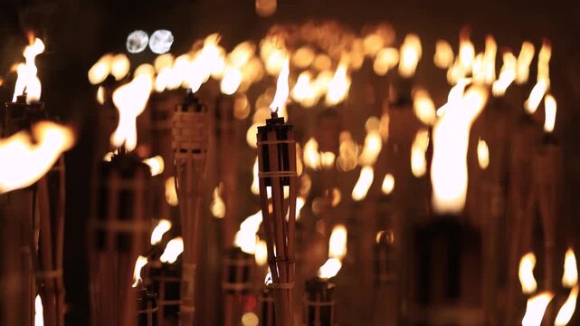 A captivating night scene of lit bamboo torches Warmflickering flames create a dramatic glow against the dark with soft bokeh lightsancient ritual cultural celebration spirit in a timeless spectacle
