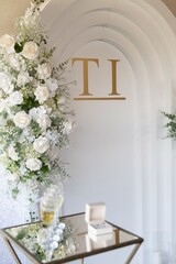 Elegant white wedding arch with floral arrangement and champagne glasses