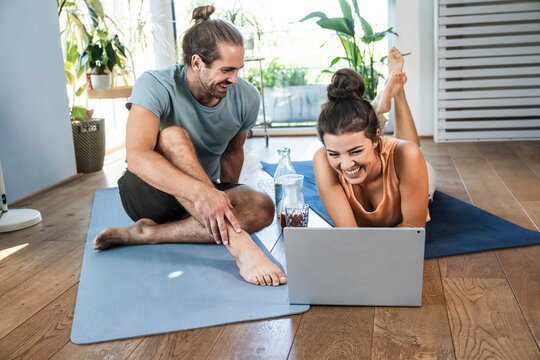 Happy man with woman using laptop on mat at home