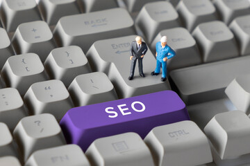 Miniature Business Figures Standing on Keyboard Button with Text SEO. Symbolizing search engine optimization, digital marketing, online visibility, and website performance strategies.