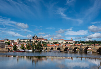 Prague, Czech Republic, August 9, 2023. A shot with an enchanting view of the castle and cathedral dominating the hill, with the Vltava River flowing at its foot, traversed by tourist boats.