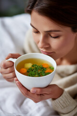 Woman enjoying warm chicken soup for comfort and health