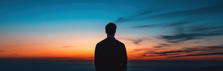Silhouette of a Person Against a Vibrant Sunset over the Horizon