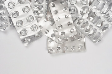 Several empty and crumpled silver medicine blister packs are piled along the top edge of a plain white background with ample copy space below.