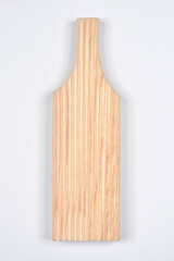 A light-colored, natural wooden gnocchi board with parallel grooves is positioned vertically on a clean, plain light gray background