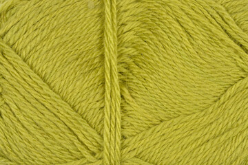A close-up shot displays the textured surface of a ball of yarn in a vibrant olive-green color