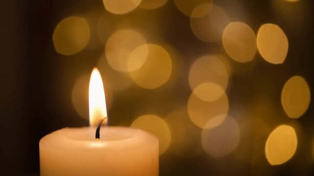 Serene glowing candle flame creating a tranquil and warm atmosphere with beautiful golden bokeh lights in the background