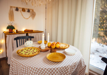 Cozy dining table set with delicious baked goods, fresh apples, and candles, creating a warm atmosphere for gatherings and celebrations in a rustic home setting
