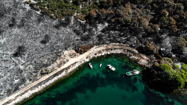 Aerial view of a striking contrast between the scorched earth and the vibrant turquoise waters near Zaton, Zadar County, Croatia.