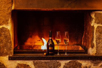 Elegant champagne bottle with two flutes placed on a rustic stone fireplace, warm flames flickering in the background, creating a cozy and inviting atmosphere for celebration