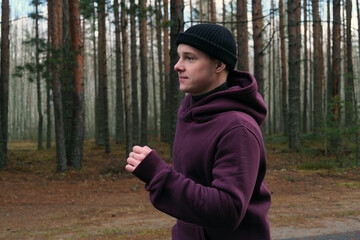 Man running in forest wearing hoodie and beanie