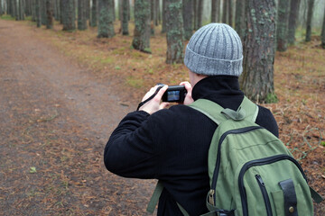 Man photographing forest during autumn hiking trip