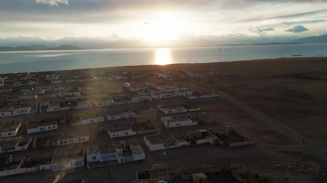Aerial view of Karakul village on the shore of Lake Karakul, Pamir Mountains, Tajikistan during sunset with traditional stone house