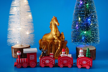 A toy Christmas train and a horse figurine with the number 2026.