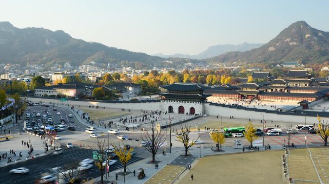 Gyeongbokgung Palace timelapse on a sunny autumn day with city traffic and people, clear sky and mountains in the background.