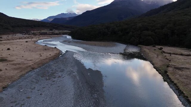 Low water level of River in aspiring area of New Zealand. Dawn scene. Aerial wide shot. Rolling hills and mountains with snow on the peak. Peaceful scene in nature.