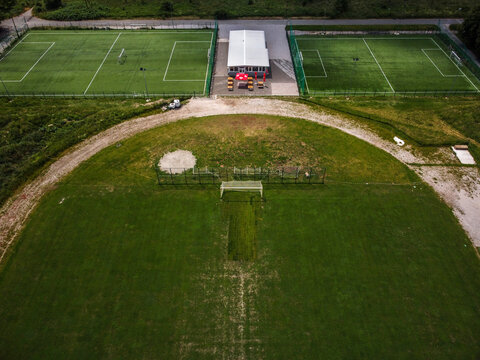 Aerial view of vibrant green soccer fields and a semi-circular training ground create a tapestry of athletic spaces, Zagreb, Croatia.