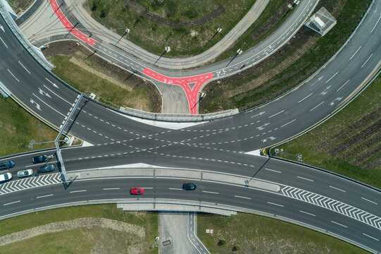 Aerial view of a complex interchange with curving ramps and bridges, where cars flow seamlessly amidst patches of green, Zagreb, Croatia.