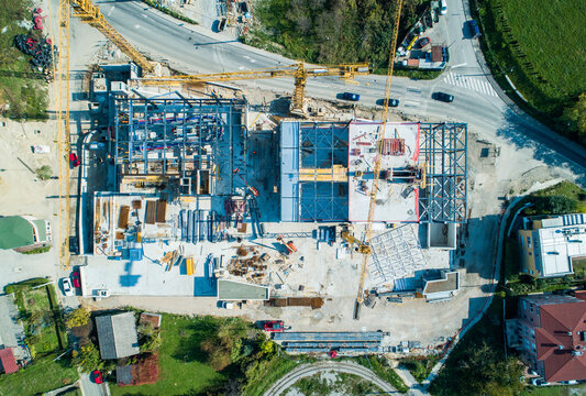 Aerial view of construction site with cranes casting long shadows over the skeletal building framework, Zagreb, Croatia.