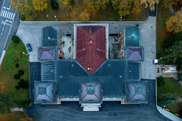 Aerial view of the Presidential Palace's symmetrical architecture, blending rich terracotta roofs with deep blues and greens, stands majestically amidst the surrounding parkland, Zagreb, Croatia.