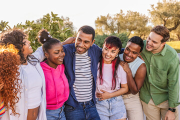 Diverse smiling young adults embracing outdoors together