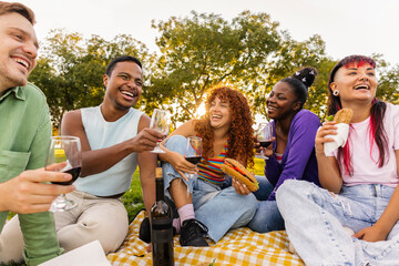 Diverse happy friends having picnic drinking wine outdoors