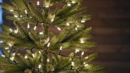 Festive close-up of an artificial evergreen Christmas tree adorned with twinkling LED string lights perfect for holiday season cheer and warm cozy atmospheres - Powered by Adobe