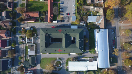 Aerial view of a large building with a courtyard, marked by red crosses on the roof, surrounded by autumn trees and smaller structures, Vukovar, Vukovar-Srijem County, Croatia.