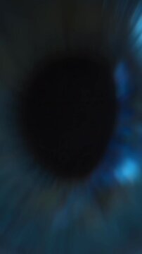 Zoom in close up of wide open human eye looking at glowing display with smartphone screen reflection on pupil. Social media addiction, doomscrolling, or insomnia concept. Vertical video