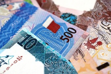 Qatari riyal money bills banknotes lies in big pile on table close up. Concept of finances and...