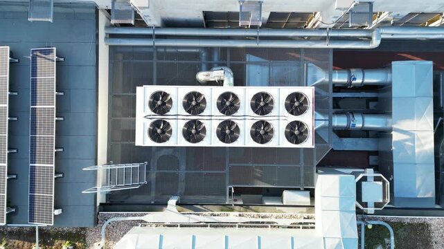 Aerial view of rooftop cooling units with modern ventilation systems, showcasing a seamless transition from overhead perspective to detailed equipment, emphasizing urban architecture and energy effici
