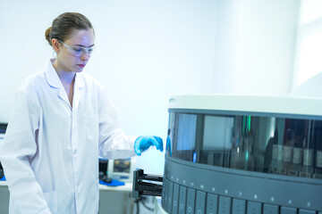 A pharmaceutical Quality Control QC team ensures GxP compliance. Two scientists review an electronic batch record on a tablet while a third performs a required analytical test.