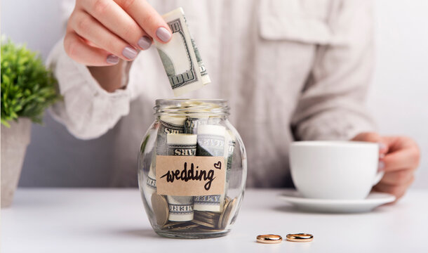 Wedding savings. Woman throwing dollars in jar with money for wedding